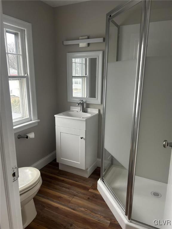 bathroom with an enclosed shower, hardwood / wood-style floors, vanity, and toilet