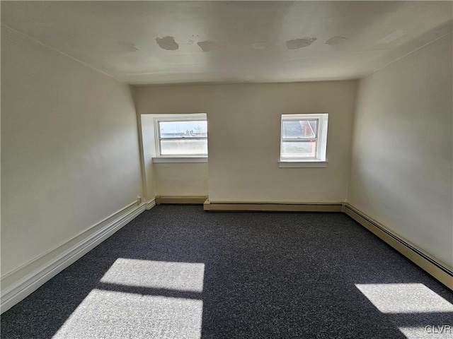 unfurnished room with a baseboard radiator and dark carpet