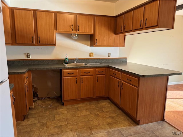 kitchen with sink, kitchen peninsula, and white refrigerator