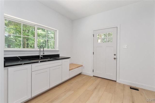 kitchen with white cabinetry, sink, and light hardwood / wood-style flooring