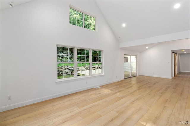 unfurnished living room featuring high vaulted ceiling and light hardwood / wood-style flooring