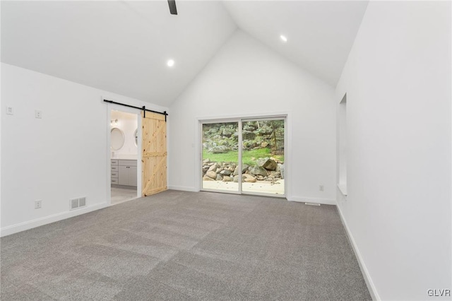 unfurnished bedroom with ensuite bathroom, access to exterior, high vaulted ceiling, light carpet, and a barn door