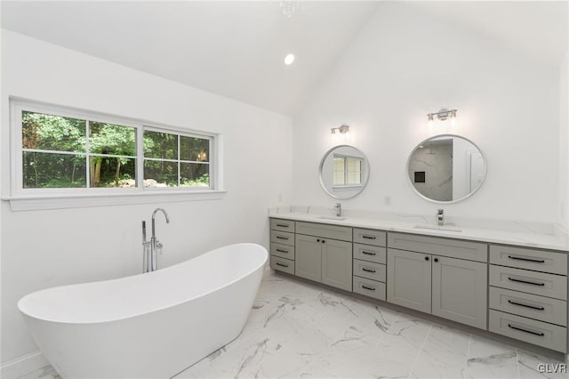 bathroom with lofted ceiling, a tub to relax in, and vanity