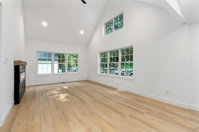 unfurnished living room featuring ceiling fan, high vaulted ceiling, and light wood-type flooring