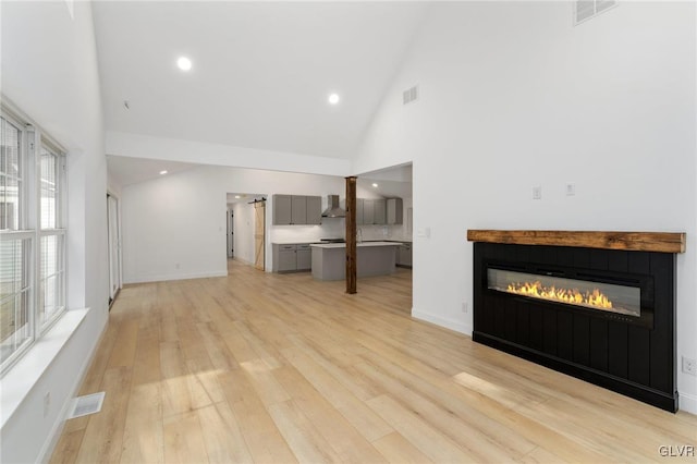 unfurnished living room with high vaulted ceiling and light hardwood / wood-style flooring