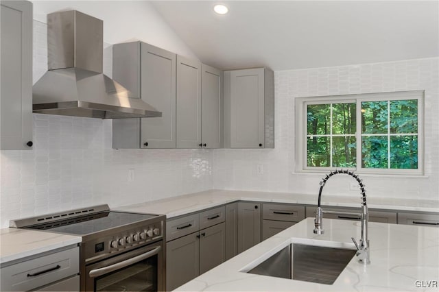 kitchen featuring sink, light stone counters, electric range, gray cabinets, and wall chimney range hood