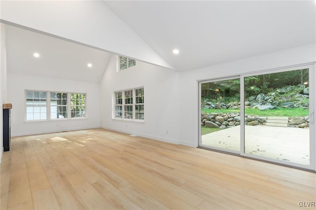 unfurnished living room with high vaulted ceiling and light hardwood / wood-style floors