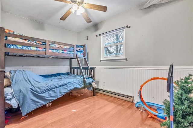 bedroom featuring hardwood / wood-style floors, a baseboard radiator, and ceiling fan