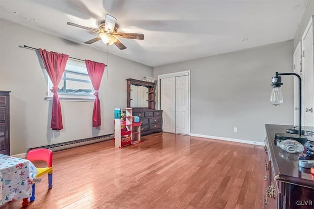 interior space with ceiling fan, light wood-type flooring, baseboard heating, and a closet