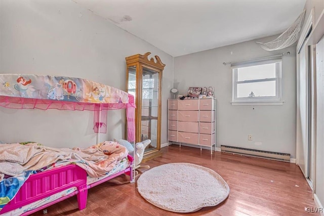 bedroom with hardwood / wood-style floors and baseboard heating