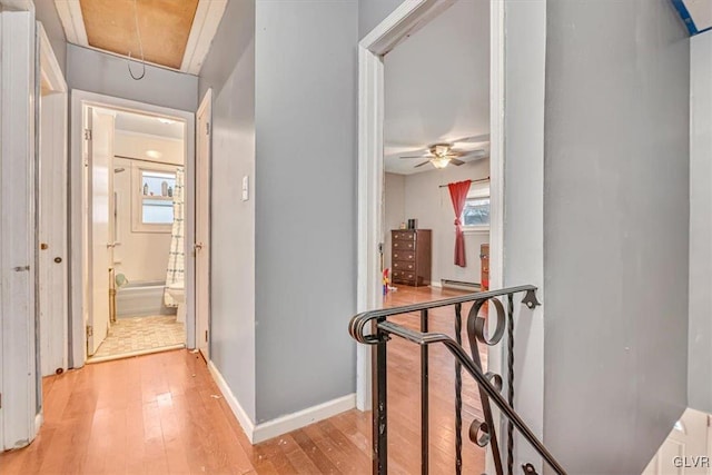 hall with baseboard heating and light wood-type flooring