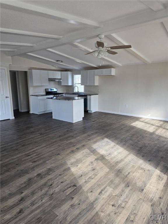 kitchen with stainless steel gas stove, vaulted ceiling with beams, a kitchen island, and open floor plan