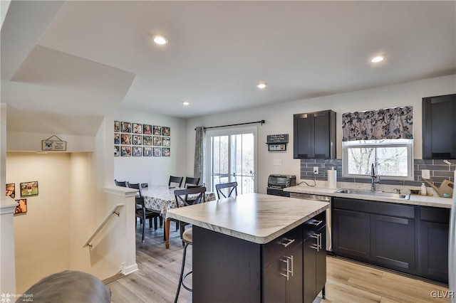 kitchen with tasteful backsplash, light hardwood / wood-style floors, a center island, and sink