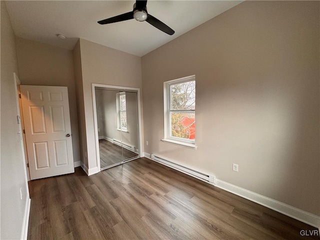 unfurnished bedroom with a baseboard heating unit, dark wood-type flooring, a closet, and ceiling fan