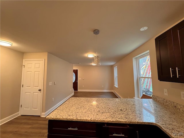 kitchen featuring light stone counters, hanging light fixtures, dark brown cabinets, and dark hardwood / wood-style floors