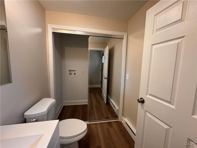 bathroom featuring hardwood / wood-style flooring, sink, baseboard heating, and toilet