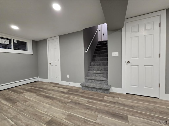 basement with wood-type flooring and a baseboard heating unit