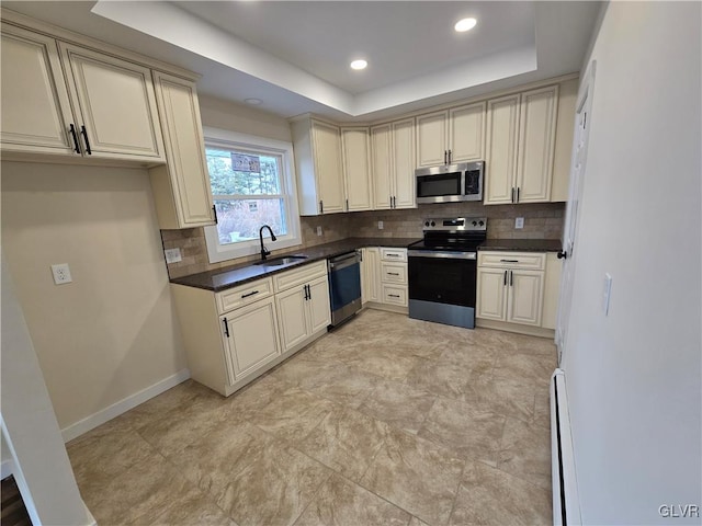 kitchen with cream cabinetry, a raised ceiling, and appliances with stainless steel finishes