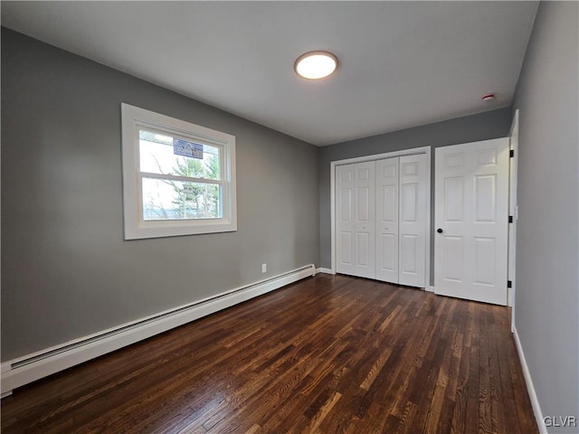 unfurnished bedroom featuring a baseboard radiator, dark hardwood / wood-style flooring, and a closet