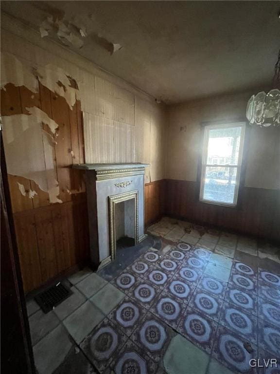 unfurnished living room with a notable chandelier, a fireplace, and wood walls