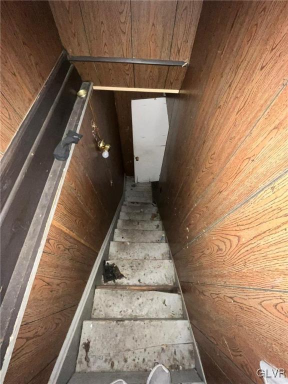 staircase featuring wooden walls