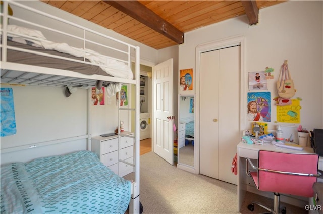 bedroom with beam ceiling, washer / dryer, light carpet, and wooden ceiling