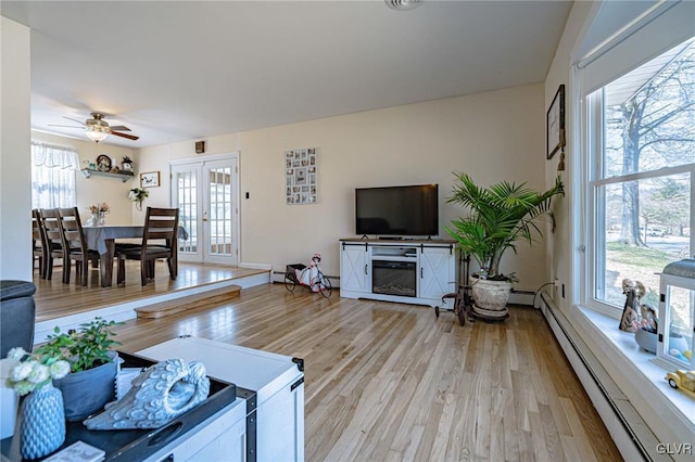 living room with a baseboard radiator, light hardwood / wood-style flooring, ceiling fan, and french doors