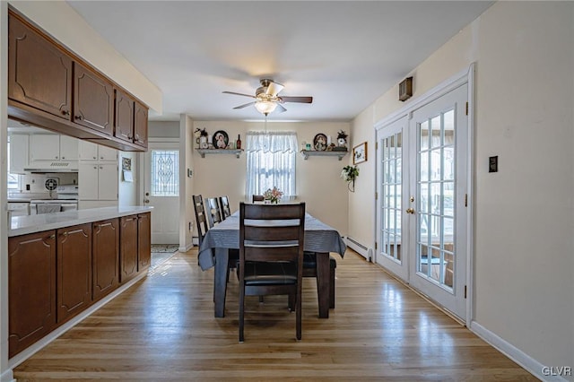 dining room featuring a baseboard heating unit, french doors, ceiling fan, and light wood-type flooring