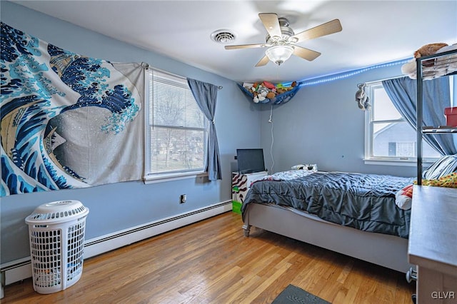 bedroom with hardwood / wood-style floors, a baseboard radiator, and ceiling fan