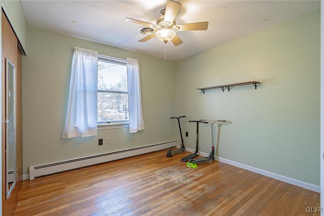 workout area with light hardwood / wood-style floors, ceiling fan, and baseboard heating