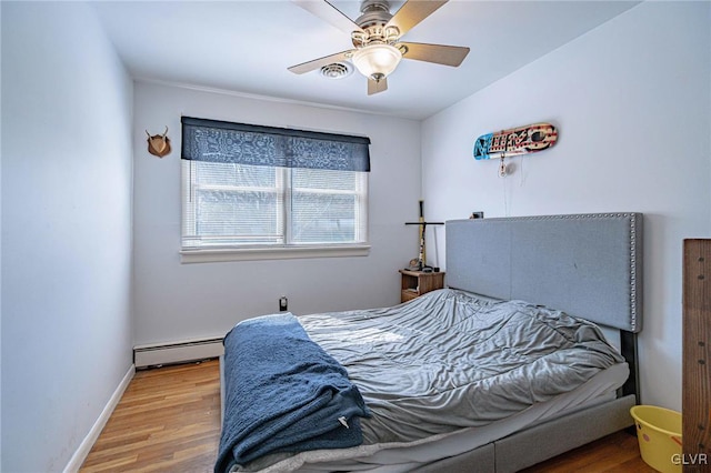 bedroom with a baseboard radiator, hardwood / wood-style floors, and ceiling fan