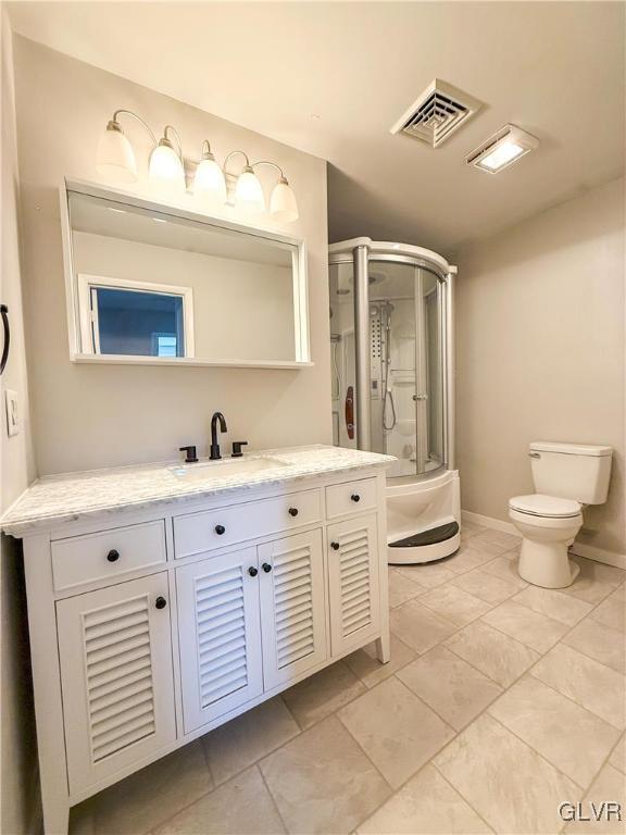 bathroom featuring vanity, an enclosed shower, and toilet