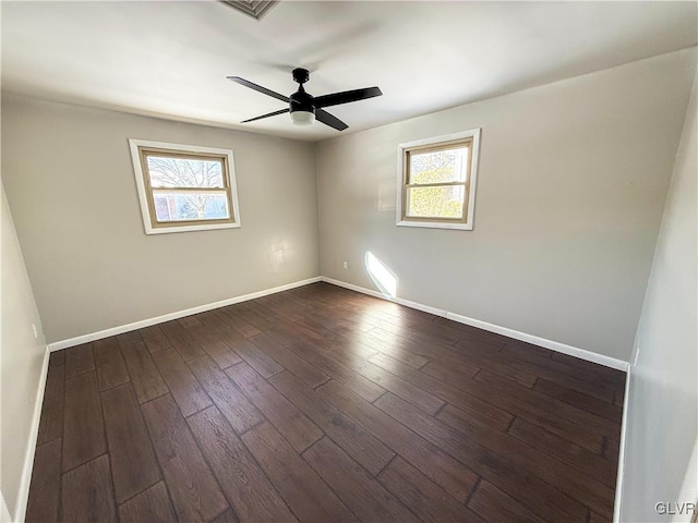 empty room with ceiling fan, dark hardwood / wood-style floors, and a wealth of natural light