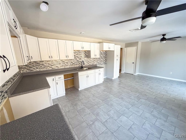 kitchen featuring ceiling fan, sink, white cabinets, and backsplash