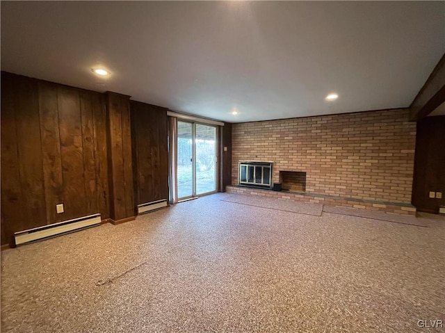 unfurnished living room with wood walls, brick wall, a fireplace, and a baseboard heating unit