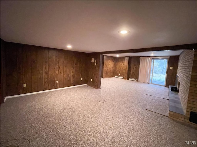 basement with a baseboard radiator, wooden walls, a fireplace, and carpet flooring