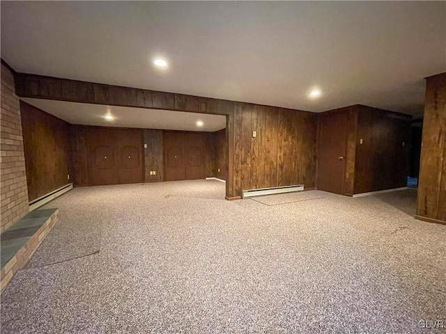 basement featuring light carpet, baseboard heating, and wood walls