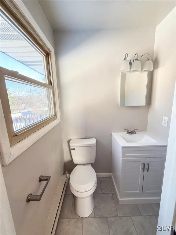 bathroom featuring vanity, a baseboard heating unit, and toilet