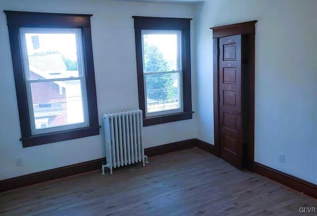 unfurnished room with radiator heating unit and hardwood / wood-style floors