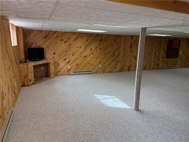 basement with wooden walls, a baseboard radiator, and carpet flooring