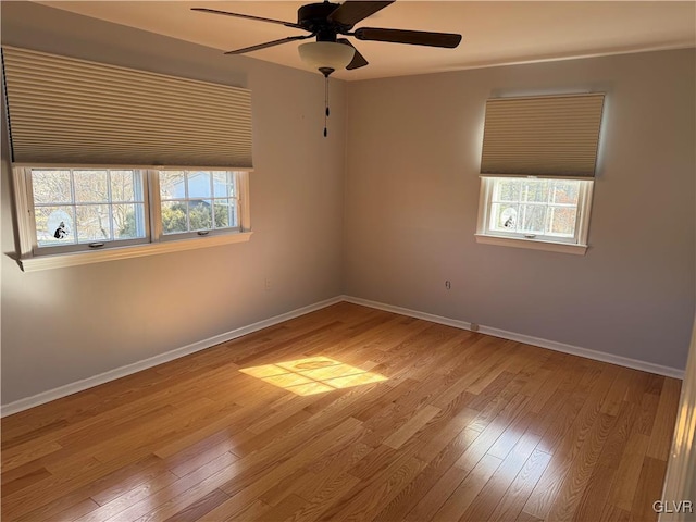 spare room with ceiling fan, a wealth of natural light, and light hardwood / wood-style floors