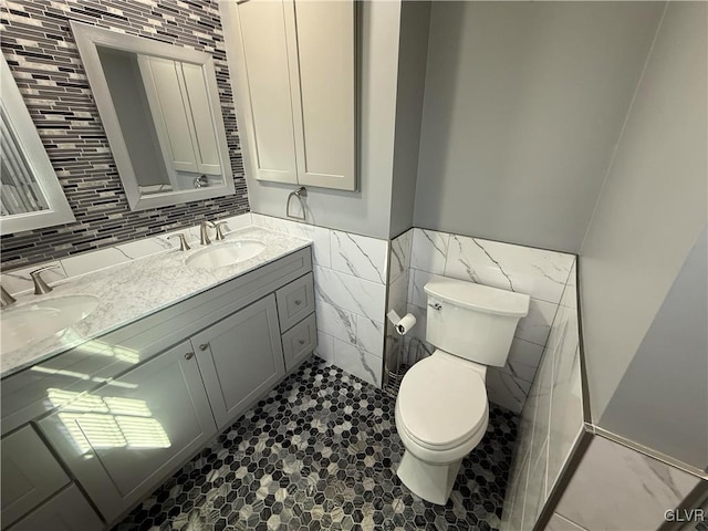 bathroom with vanity, tile walls, and toilet