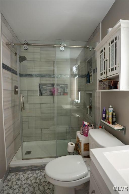 bathroom featuring vanity, an enclosed shower, tile patterned floors, and toilet