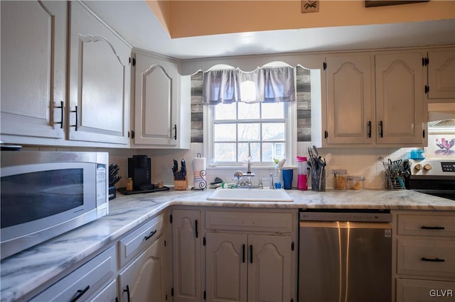 kitchen with wall chimney exhaust hood, appliances with stainless steel finishes, sink, and backsplash