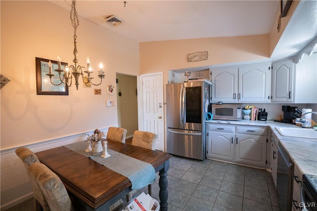 dining area featuring vaulted ceiling, an inviting chandelier, sink, and light tile patterned floors