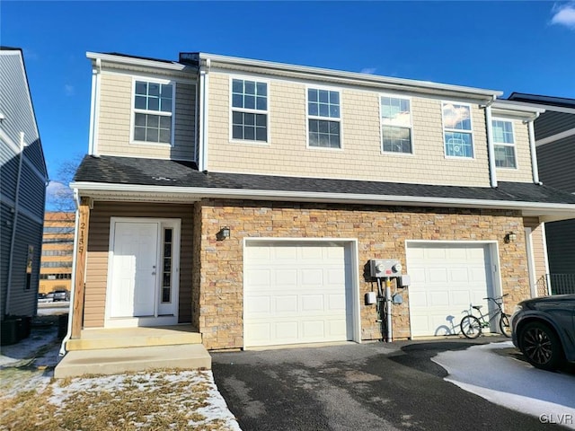 townhome / multi-family property with a garage, stone siding, driveway, and a shingled roof