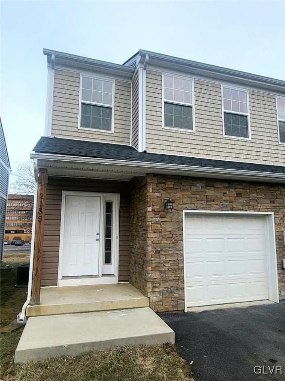 view of front of property featuring a garage and stone siding