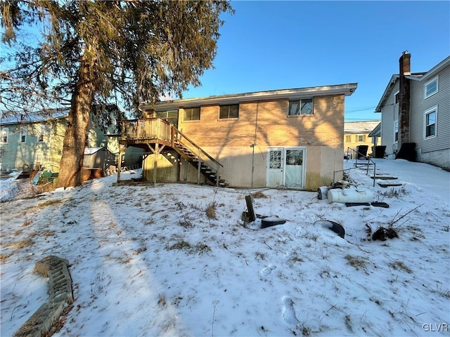 snow covered back of property with a deck