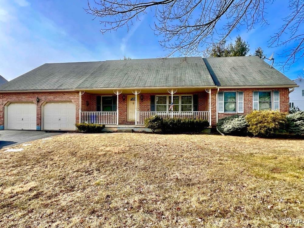 single story home featuring a garage, a porch, and a front yard