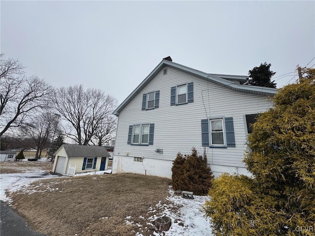 snow covered property with an outbuilding and a garage